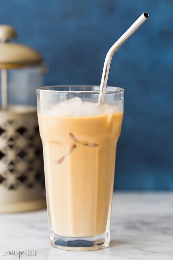 creamy cold brew coffee with stainless steel straw and blue background