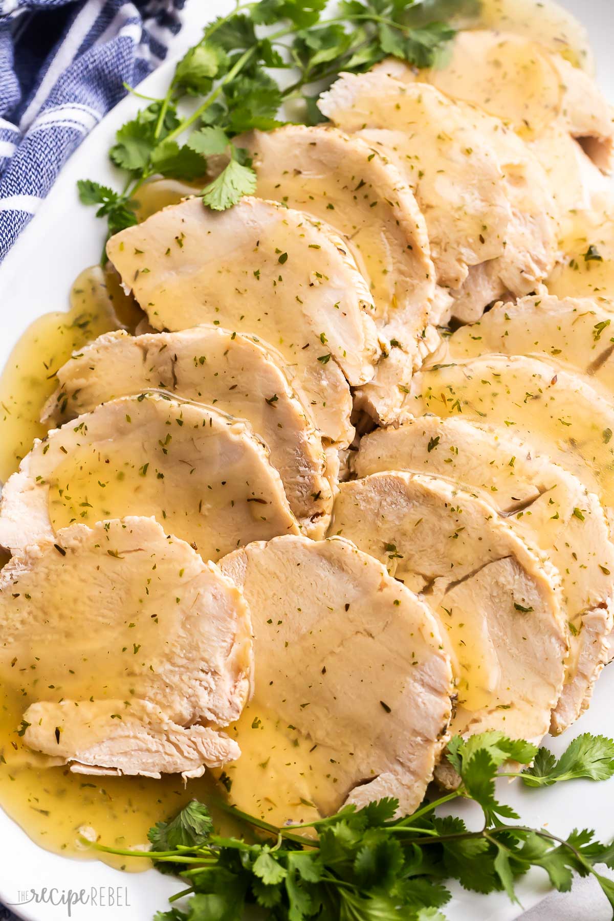 turkey breast slices on white platter with fresh parsley.