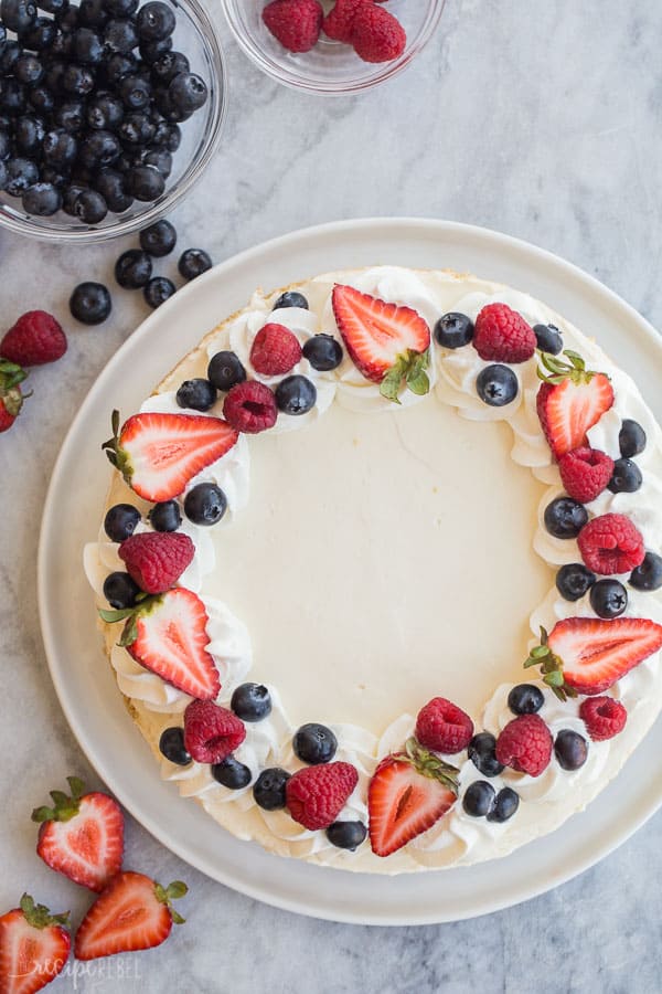 easy cheesecake recipe overhead on white plate on marble background with fresh berries on top