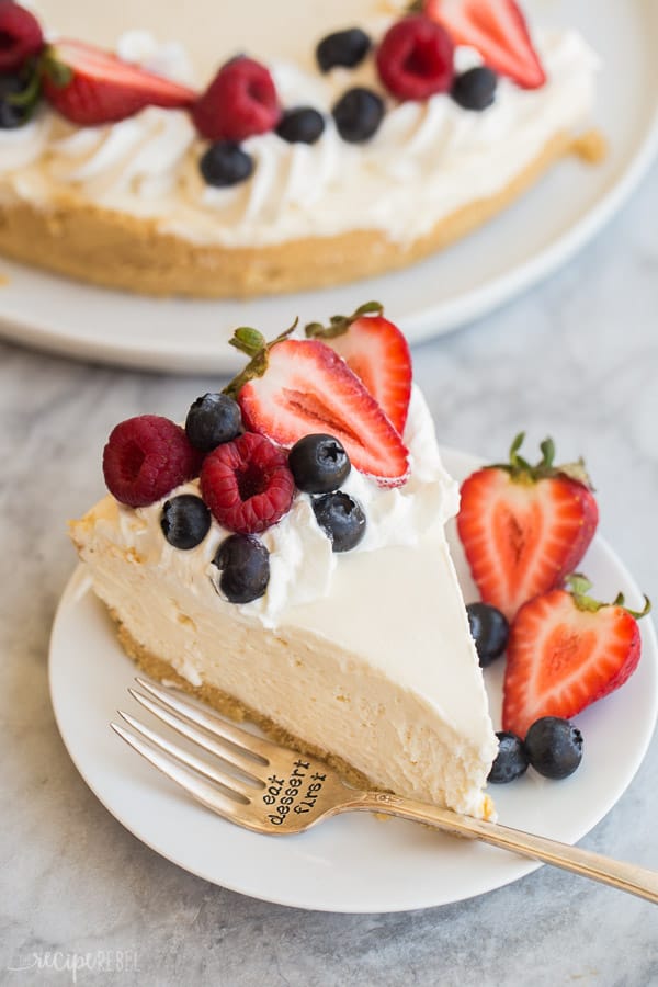easy no bake cheesecake recipe slice on white plate with fresh berries and whipped cream