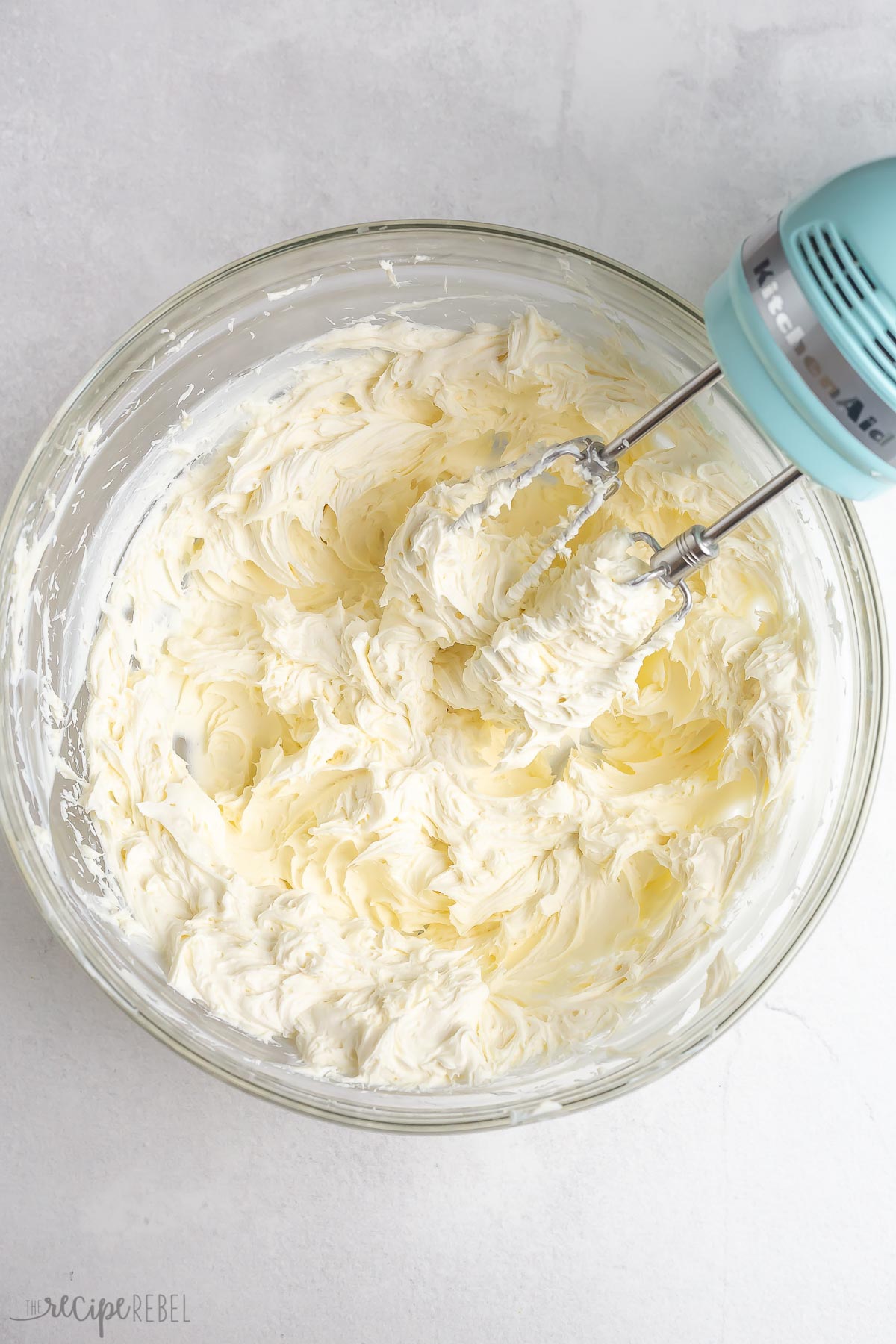 cream cheese in glass bowl with electric mixer.