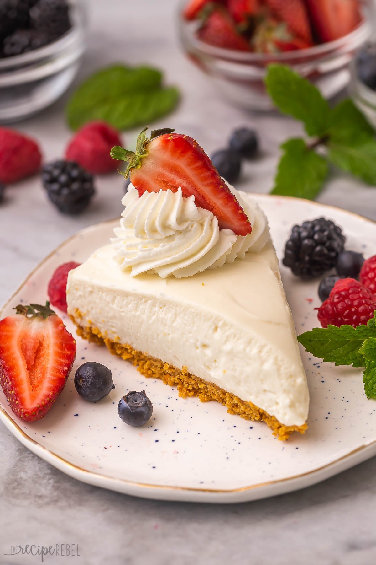 slice of easy cheesecake on white plate with whipped cream and berries.