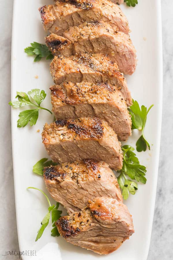 grilled pork tenderloin overhead close up on white plate on marble background