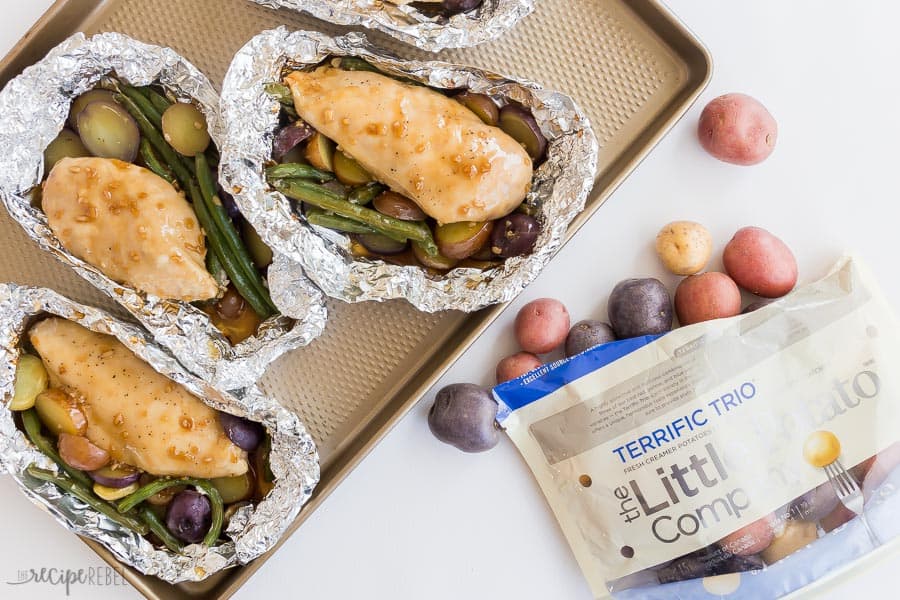 chicken foil packets on a sheet pan with Little potatoes bag and potatoes overhead