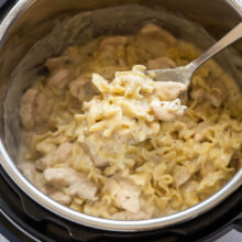 metal scoop scooping chicken and noodles from instant pot.