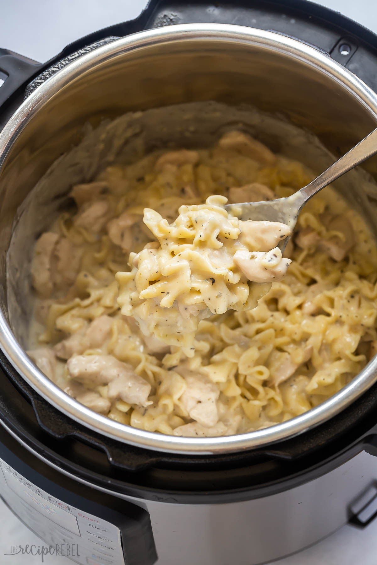 metal scoop scooping chicken and noodles from instant pot.