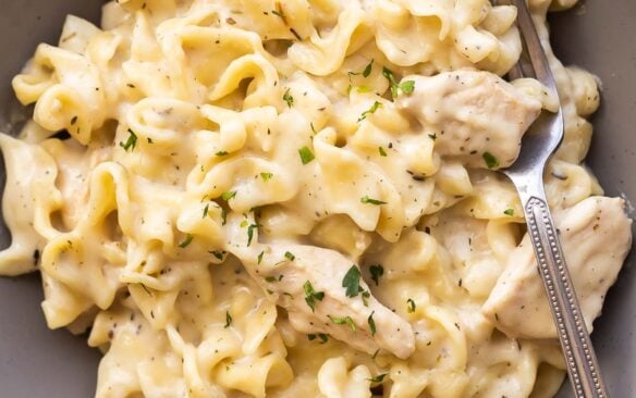 grey plate with chicken and noodles and fork.