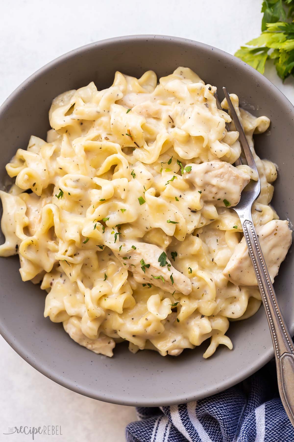 grey plate with chicken and noodles and fork.