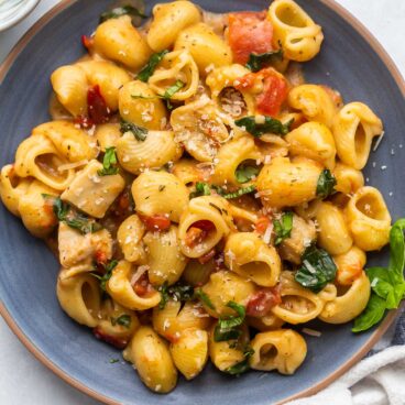 pasta on blue plate with spinach and sun dried tomatoes.