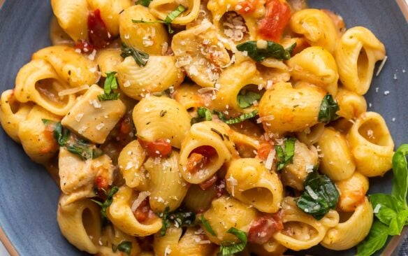 pasta on blue plate with spinach and sun dried tomatoes.