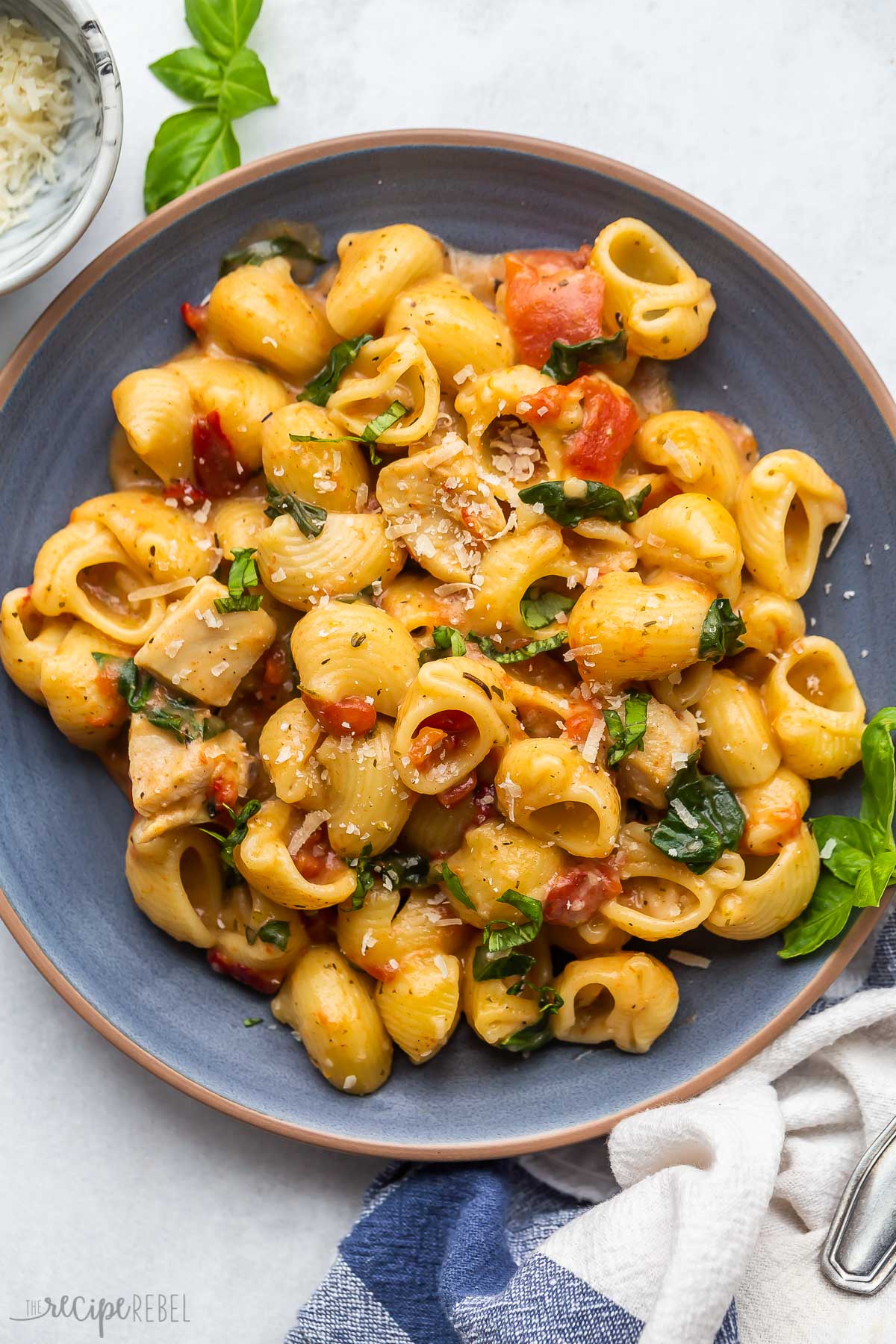 pasta on blue plate with spinach and sun dried tomatoes.