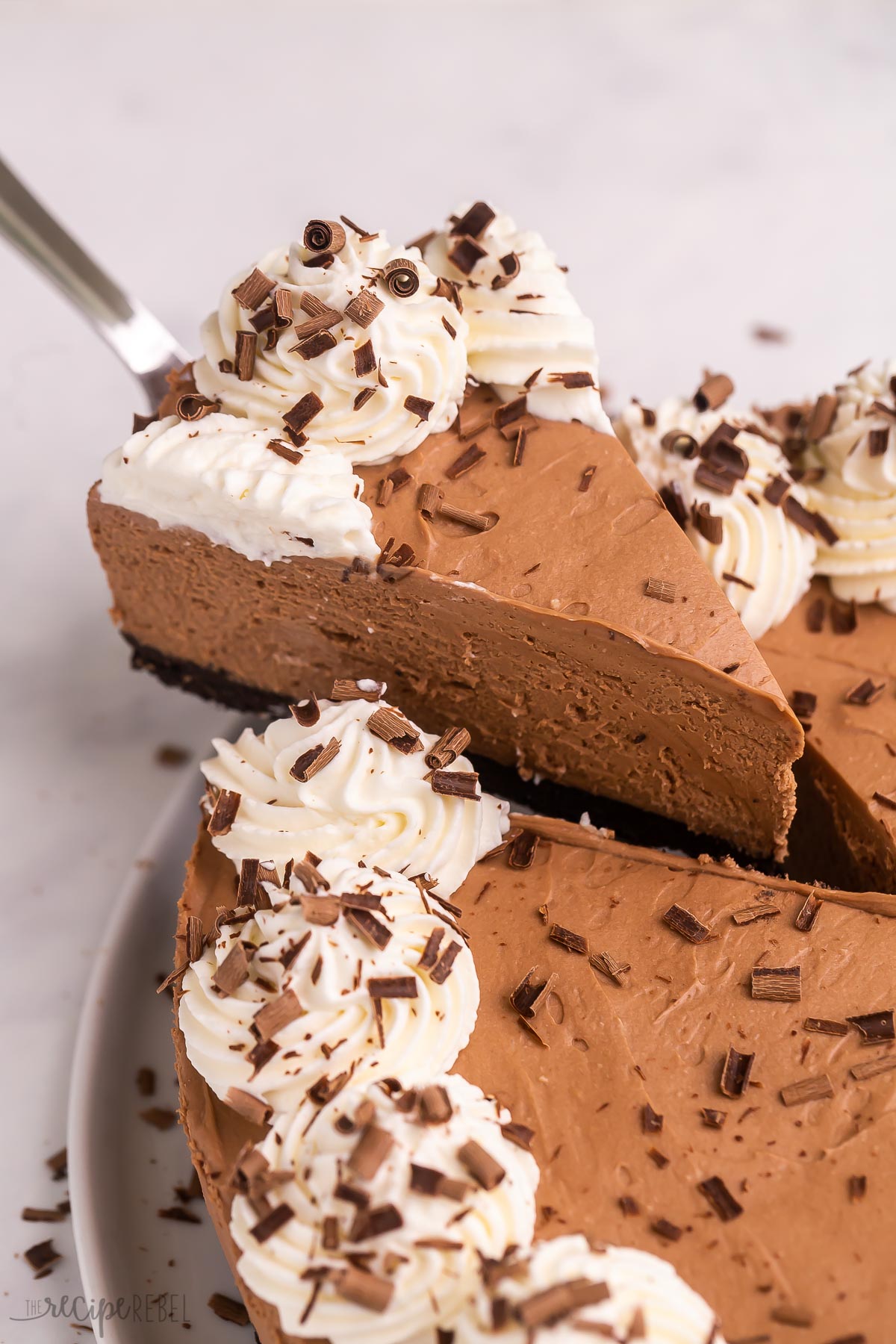 slice of no bake chocolate cheesecake being lifted out of the whole.