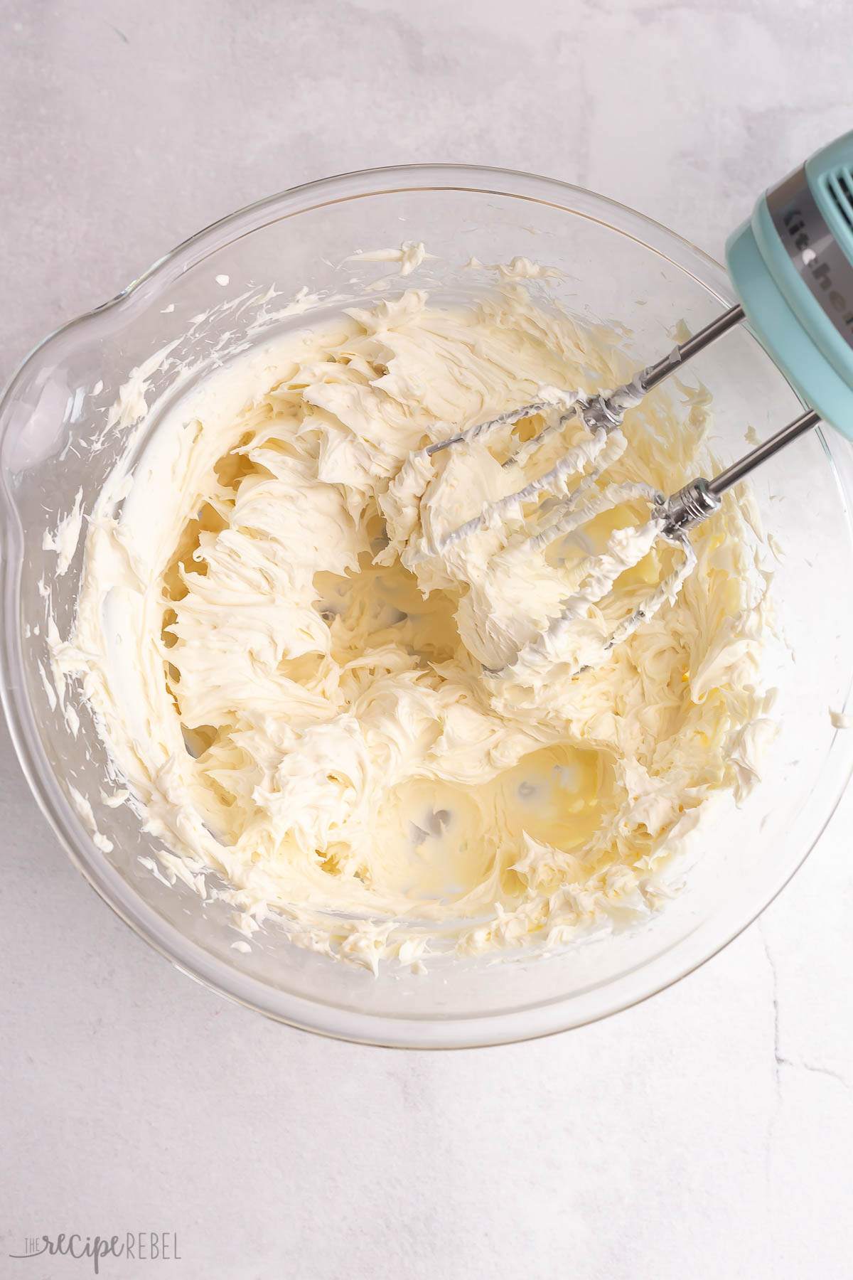 cream cheese in a glass bowl with electric mixer.