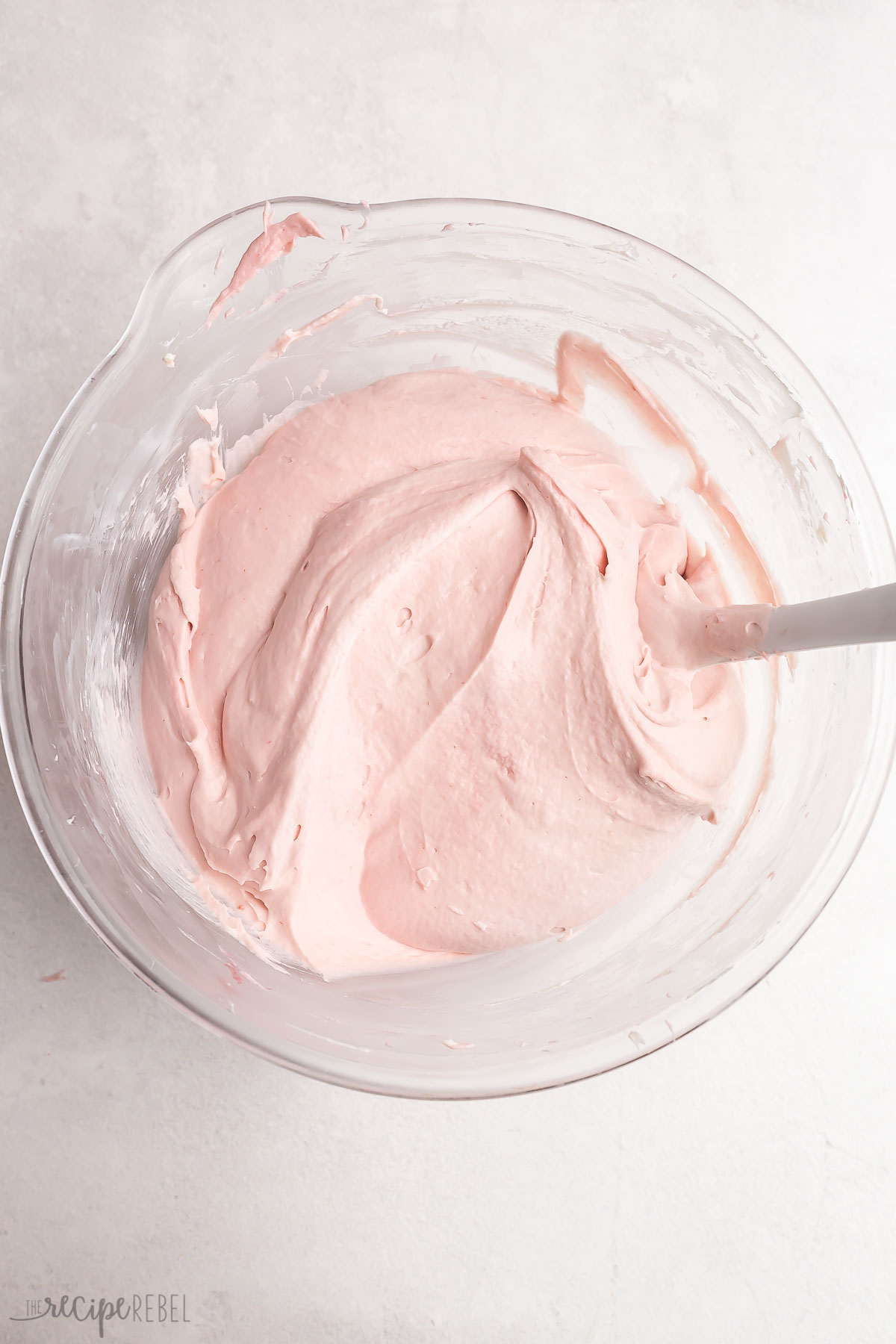 raspberry cheesecake mixture in a glass bowl with spatula.