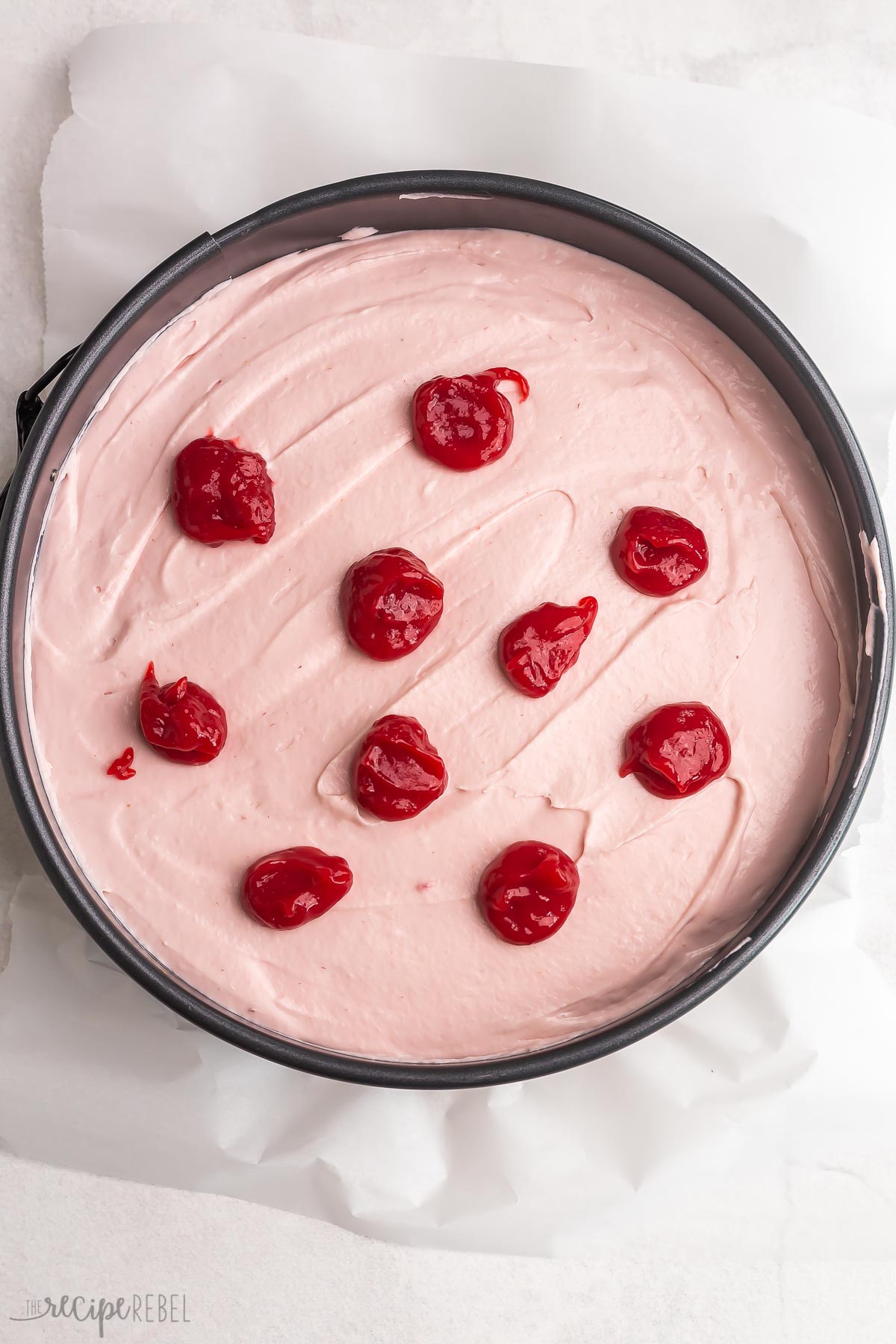 drops of raspberry puree on top of raspberry cheesecake.