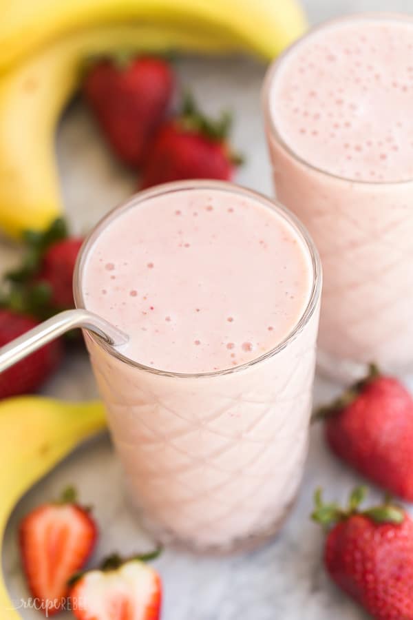 strawberry banana smoothie overhead with steel straw and fresh fruit all around