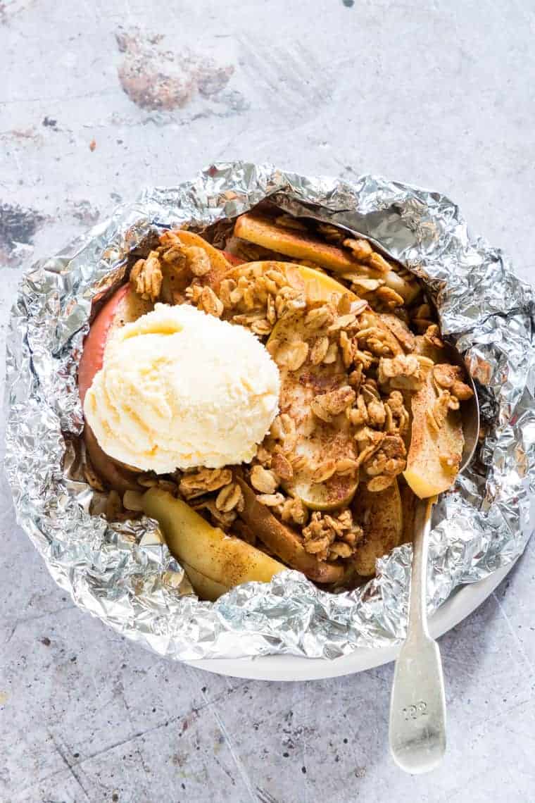 campfire apple crisp in foil pack with vanilla ice cream and spoon