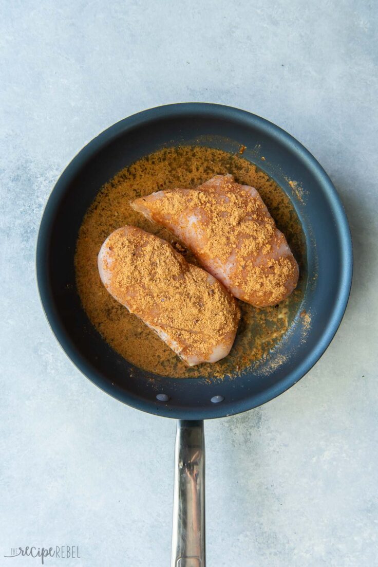 raw chicken breasts in pan with taco seasoning ready to cook
