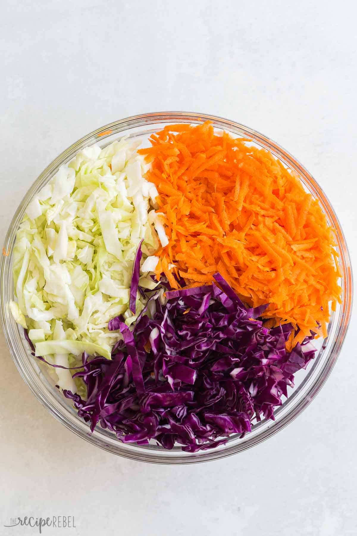 This easy Homemade Coleslaw recipe is way better than store bought! Made with shredded cabbage and a simple homemade coleslaw dressing everyone loves. #salad #recipe #sidedish | side dishes | side dish recipes | cabbage recipe | cabbage recipes | salad recipes | summer side dishes | summer recipes | bbq sides | green cabbage, red cabbage and shredded carrot in a bowl to make coleslaw.