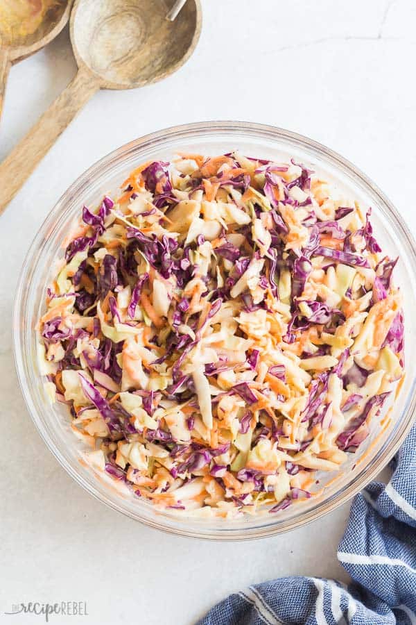 coleslaw recipe overhead in glass bowl on white background with blue towel