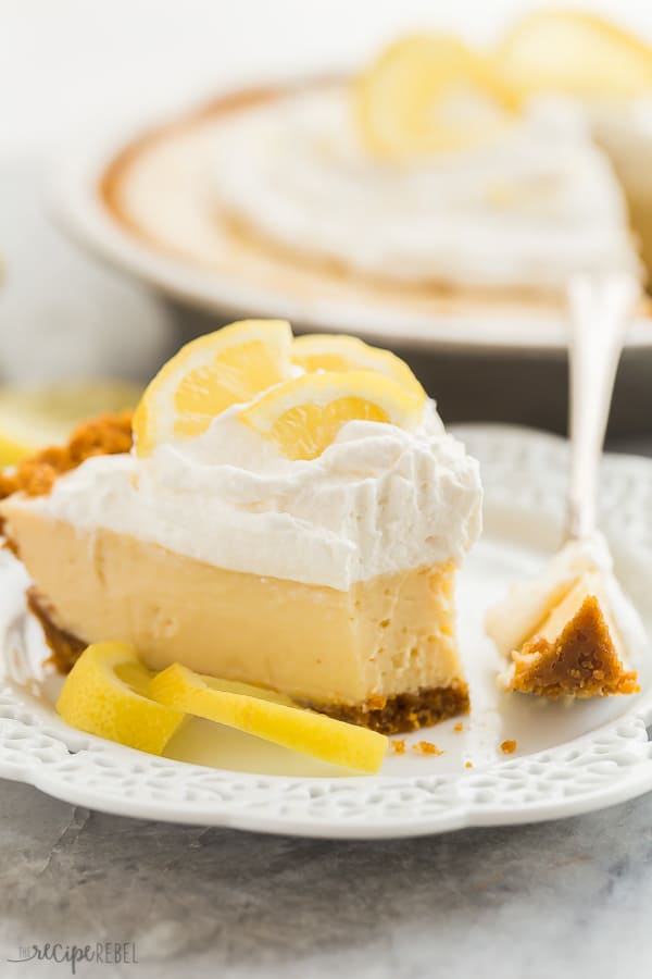 lemon icebox pie slice with bite close up with whipped cream and lemon slices