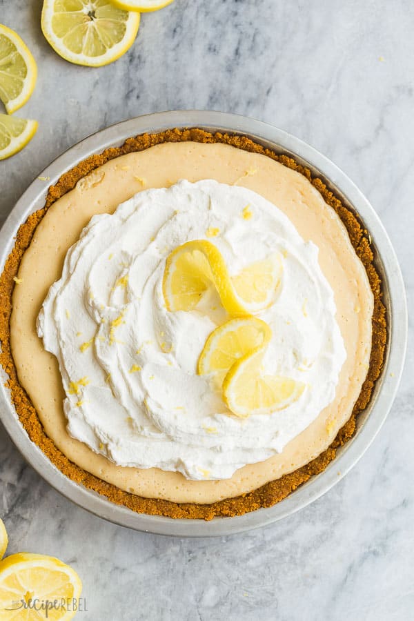 This Lemon Icebox Pie is the perfect combination of sweet and tangy, made with condensed milk, egg yolks and tons of fresh lemon, topped with sweetened whipped cream for an irresistible lemon dessert! #lemon #dessert #pie #recipes #pierecipe lemon icebox pie whole overhead with whipped cream and two lemon slices