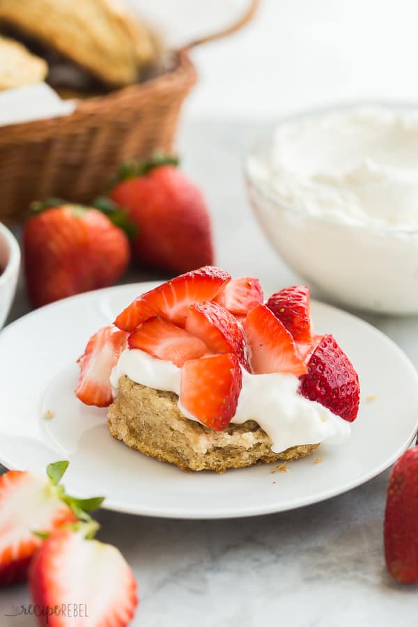 This Strawberry Shortcake recipe is made completely from scratch, but make ahead and freezer options make this an easy strawberry dessert you'll enjoy all summer long! #strawberry #strawberries #cake #dessert #recipe strawberry shortcake on white plate with no top biscuit and fresh strawberries