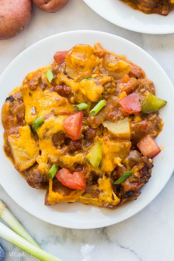 cheeseburger casserole on white plate with green onions garnish