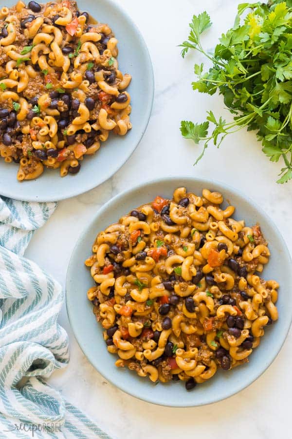 instant pot chili mac and cheese overhead on two blue plates on white background with blue towel