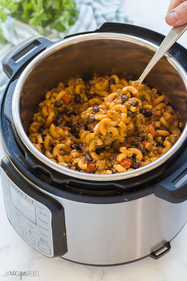 instant pot pasta with chili in pressure cooker being scooped in a metal spoon