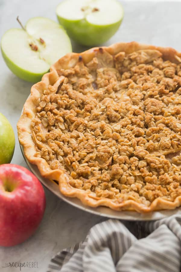 apple crumble pie whole in pie plate with apples along the edge