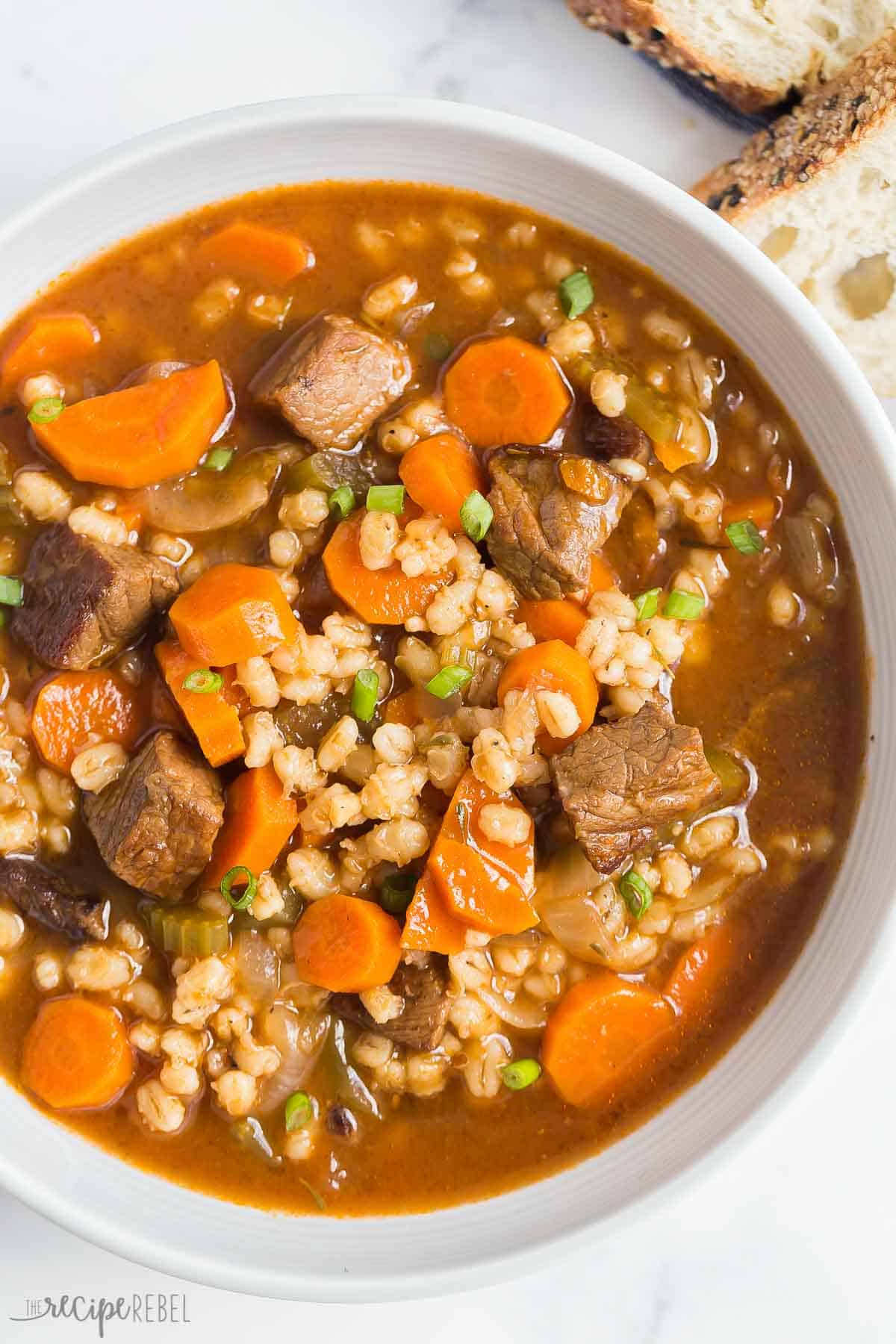 This easy Beef Barley Soup is a hearty, healthy soup recipe that is made with tender chunks of beef, loads of vegetables and pearl barley. Make ahead and freezer friendly. #beef #soup #recipe | easy soup recipes | healthy soup | beef roast | steak recipes | beef recipes | comfort food | healthy meals overhead image of a bowl of beef and barley soup with parsley.