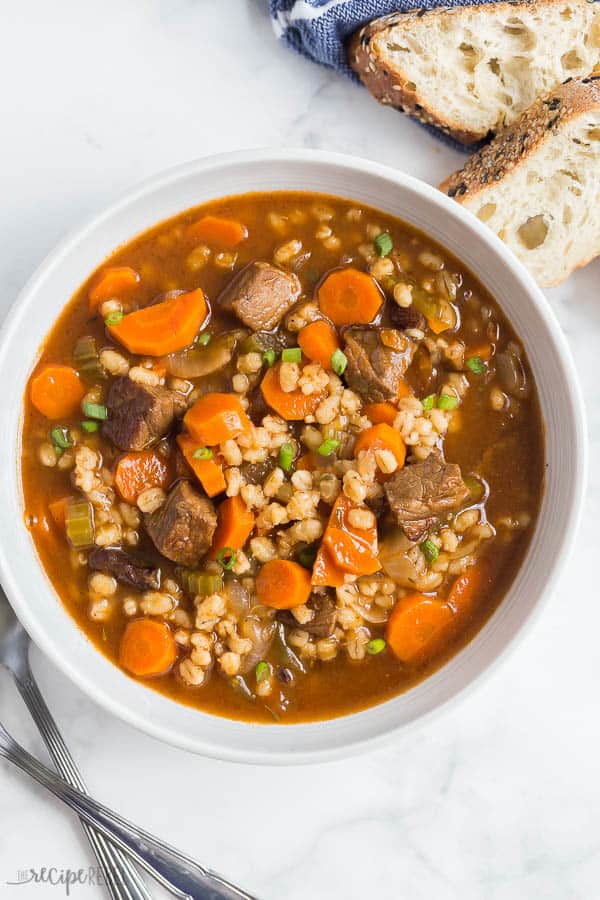 beef and barley soup in a white bowl overhead on white background