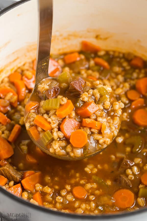 beef barley soup in pot with close up of scoop of soup