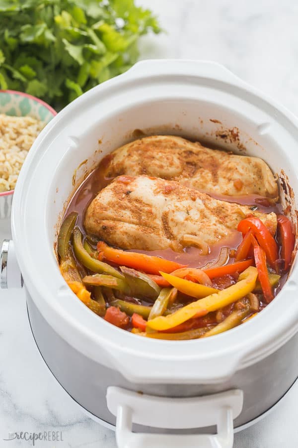 slow cooker chicken fajitas in white crockpot with rice and cilantro in the background