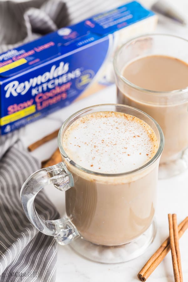 pumpkin spice latte in glass mugs with grey towel on the side and slow cooker liners in the background