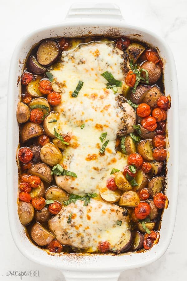 caprese chicken with potaoes and tomatoes in white baking dish overhead on white background