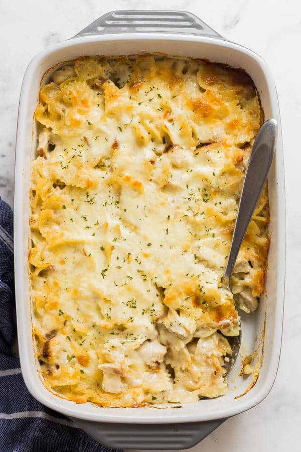 chicken alfredo bake in grey pan with spoon scooping pasta