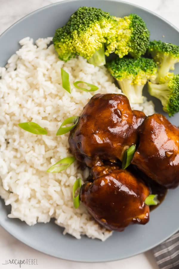 slow cooker chicken thighs in sauce close up on grey plate with broccoli and rice