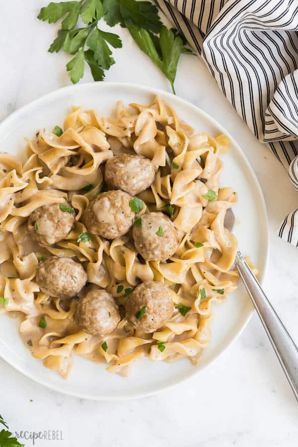 instant pot meatballs on white plate on white background with fork stuck in noodles