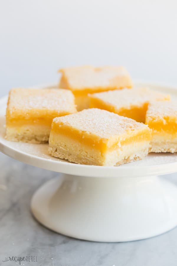 lemon cheesecake bars on white plate with marble background and white