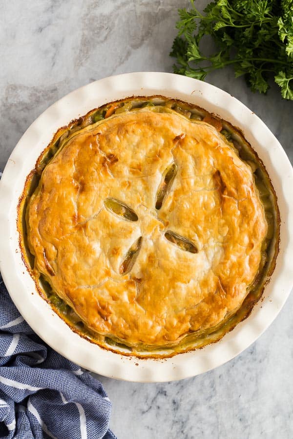 This Turkey Pot Pie is made in one pan, with tender turkey or chicken, vegetables, and a creamy gravy topped with puff pastry for an easy dinner idea that's also freezer friendly! #turkey #dinner #recipes #healthy #thanksgiving turkey pot pie overhead whole in white pie plate on marble background