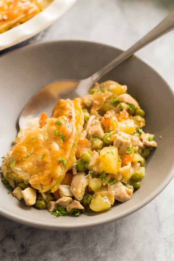 turkey pot pie in grey bowl with spoon in the bowl on marble background