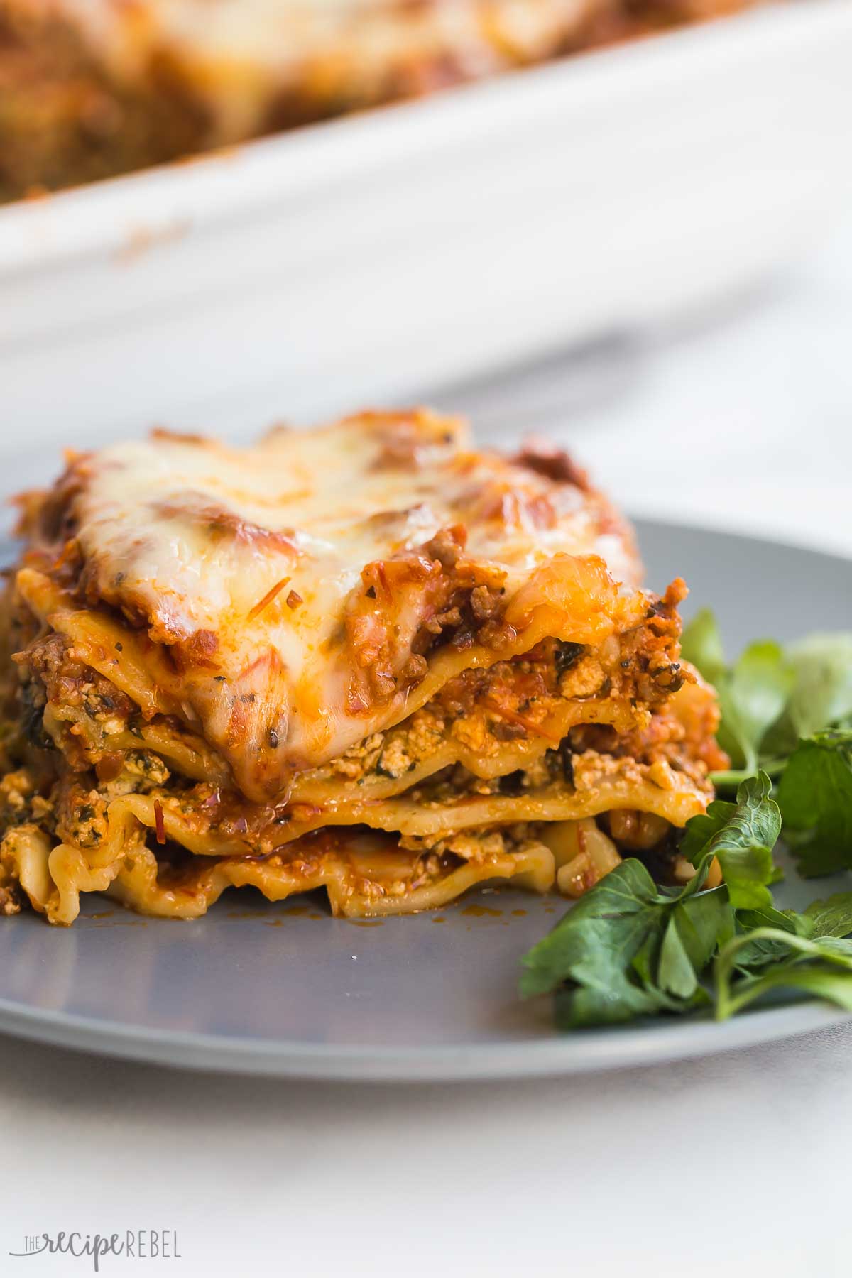 piece of lasagna on grey plate with parsley.