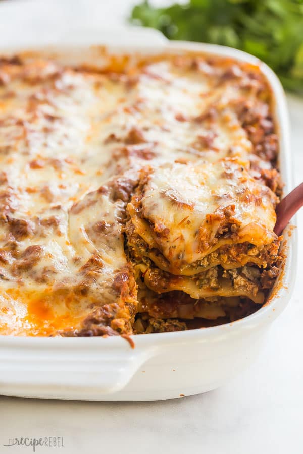 easy lasagna recipe piece being scooped out of white baking dish