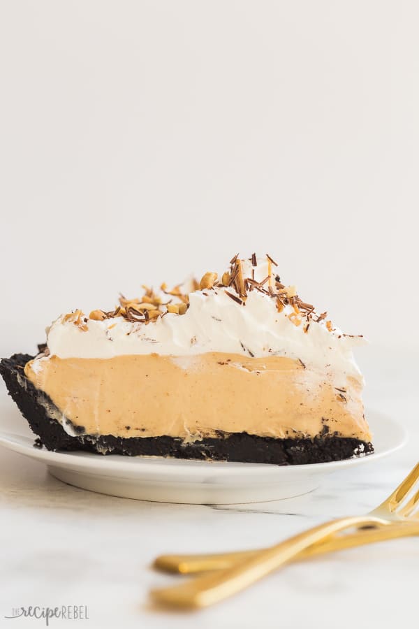 This Peanut Butter Pie is completely no bake and made with a chocolate Oreo crust, peanut butter cream cheese filling, and topped with more chocolate! Step by step recipe video down below. #peanutbutter #pie #nobake #dessert #recipes peanut butter pie slice close up on white plate on white marble background