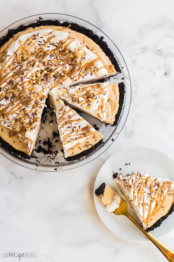 This Peanut Butter Pie is completely no bake and made with a chocolate Oreo crust, peanut butter cream cheese filling, and topped with more chocolate! Step by step recipe video down below. #peanutbutter #pie #nobake #dessert #recipes peanut butter pie sliced overhead with one slice on white plate on white background