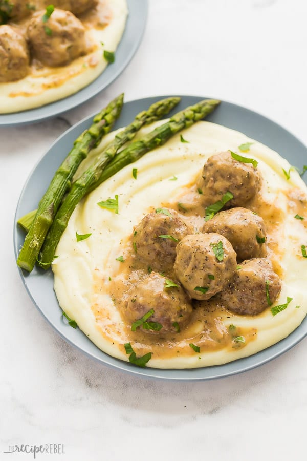swedish meatballs in gravy on mashed potatoes on grey plate with white background