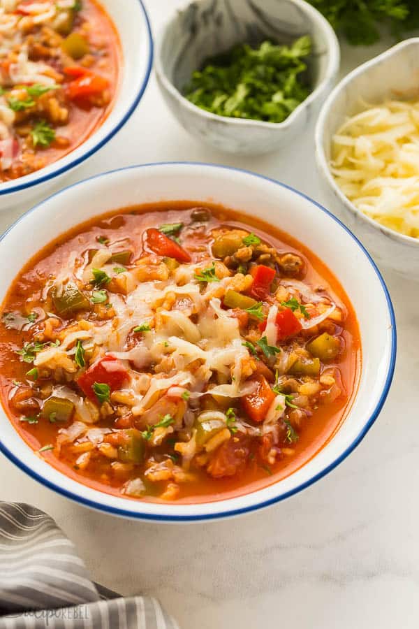 stuffed pepper soup in white bowl close up with shredded cheese