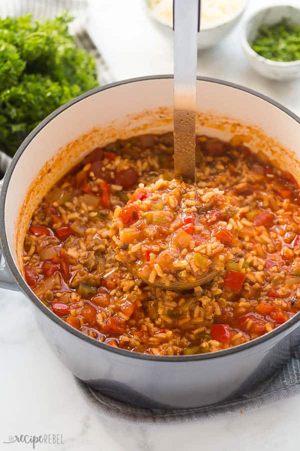 stuffed pepper soup in large grey dutch oven with scoop being pulled out